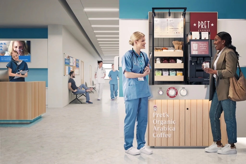 a nurse and a second woman chatting next to a Pret express machine a nurse and a second woman chatting next to a Pret express machine